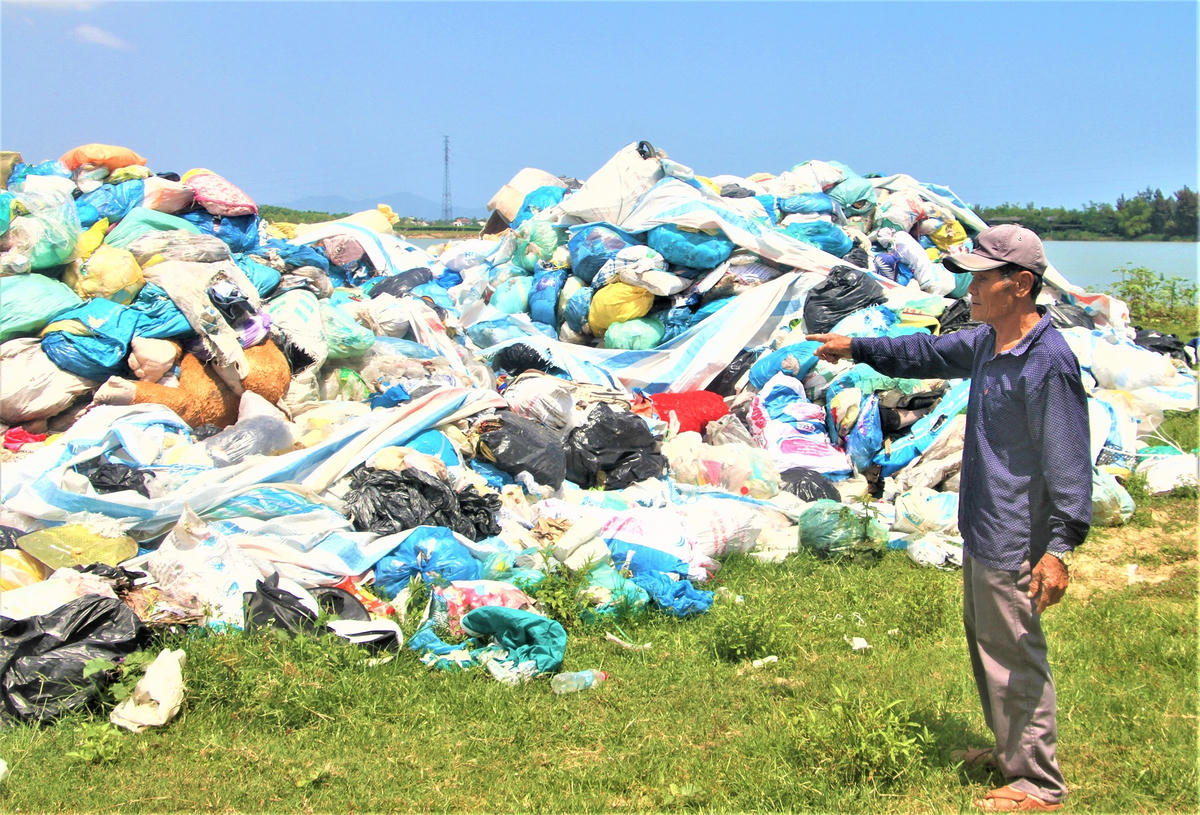 Ông Nguyễn Văn Thư chỉ bãi tập kết rác ở thôn Mỹ Phước bốc mùi hôi thối. Ảnh: Tấn Thành.