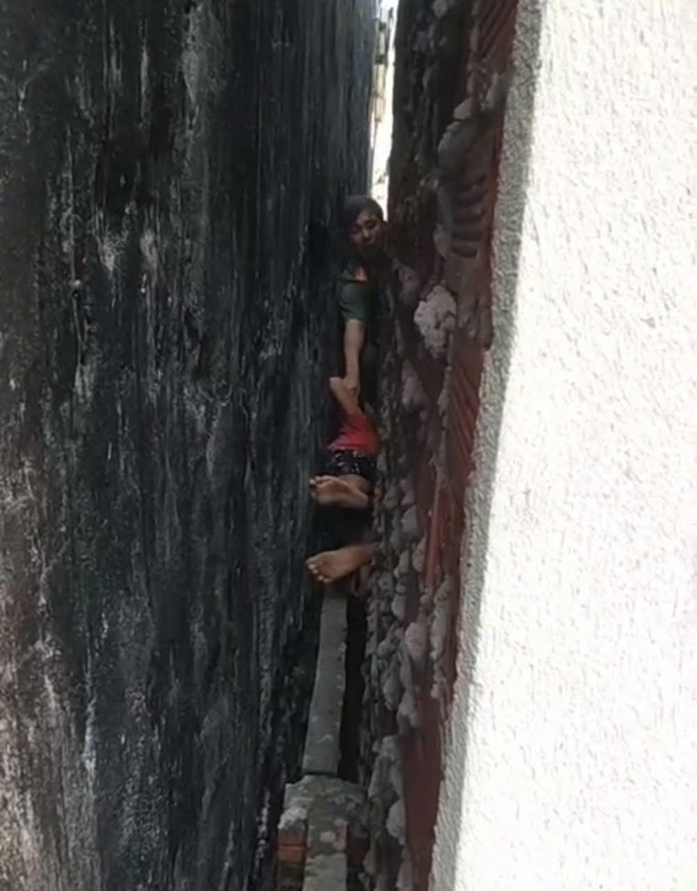 Bằng các biện pháp nghiệp vụ, lực lượng chức năng tiếp cận được bé trai bị kẹt cứng giữa 2 bức tường. Ảnh: CA.