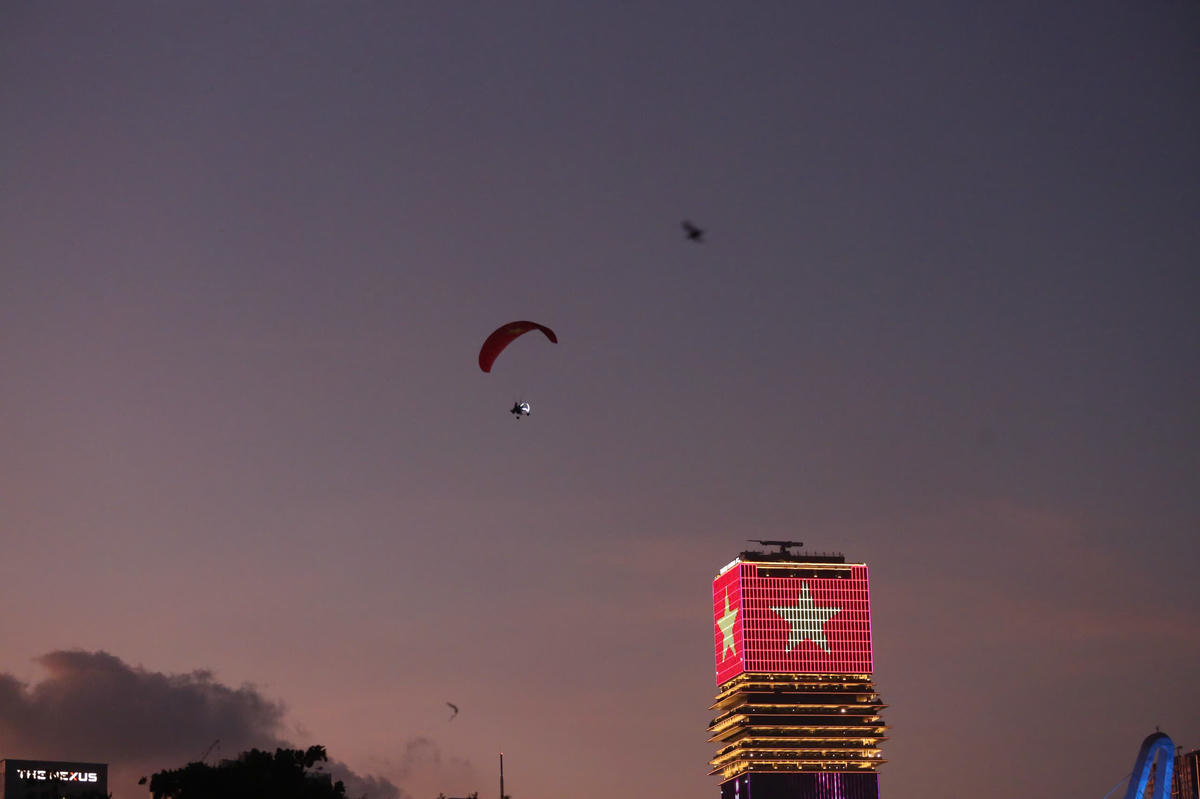 Hình ảnh dù lượn bay vòng qua Khu đô thị mới Thủ Thiêm, với nền dù là lá cờ đỏ sao vàng. Ảnh: Lâm Quang Quý.