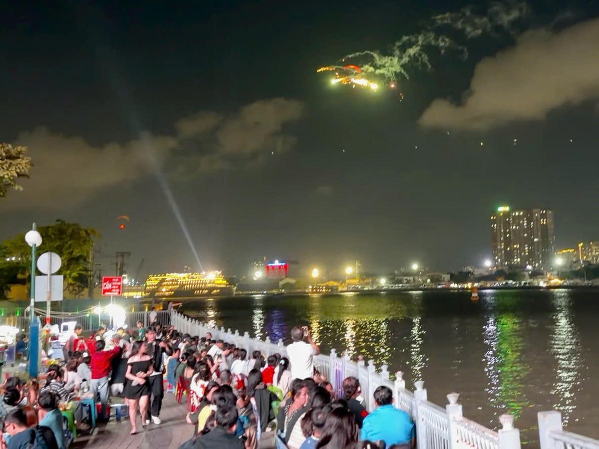 Người dân tập trung hai bên bờ sông để xem biểu diễn dù lượn. Ảnh: Hoàng Hùng.