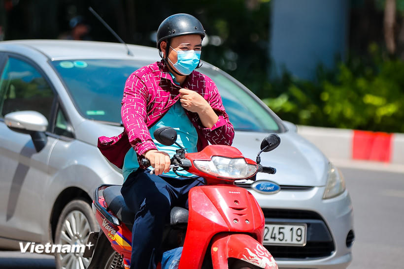 Người dân di chuyển dưới trời nắng gắt. (Ảnh: Hoài Nam/Vietnam+).