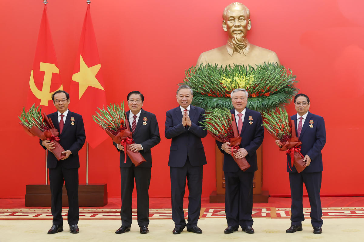 Tổng Bí thư Tô Lâm tặng hoa chúc mừng các đồng chí được nhận Huân chương Quân công hạng nhất - Ảnh: VGP/Nhật Bắc