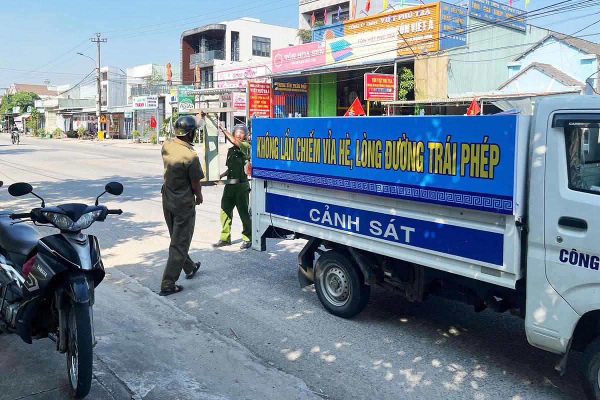 Lực lượng chức năng xã Chiên Đàn xử lý tình trạng lấn chiếm vỉa hè buôn bán. Ảnh: CV.