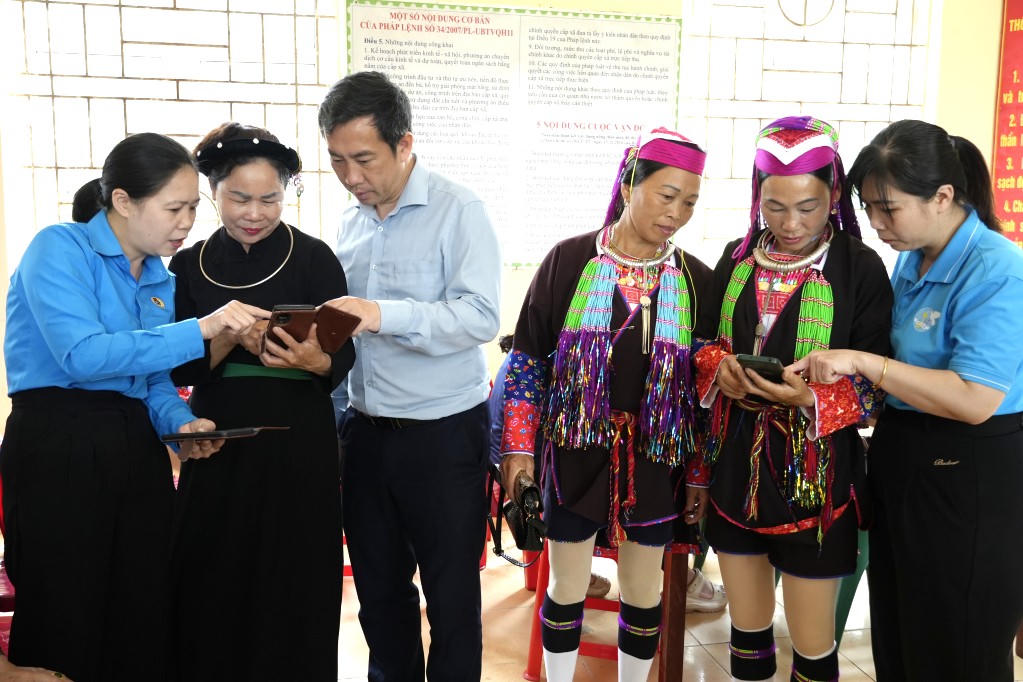  Cán bộ Mặt trận và các tổ chức chính trị - xã hội xã Tiên Yên (tỉnh Quảng Ninh) hướng dẫn bà con đồng bào thôn Nà Cà sử dụng các phần mềm, ứng dụng VNeID.
