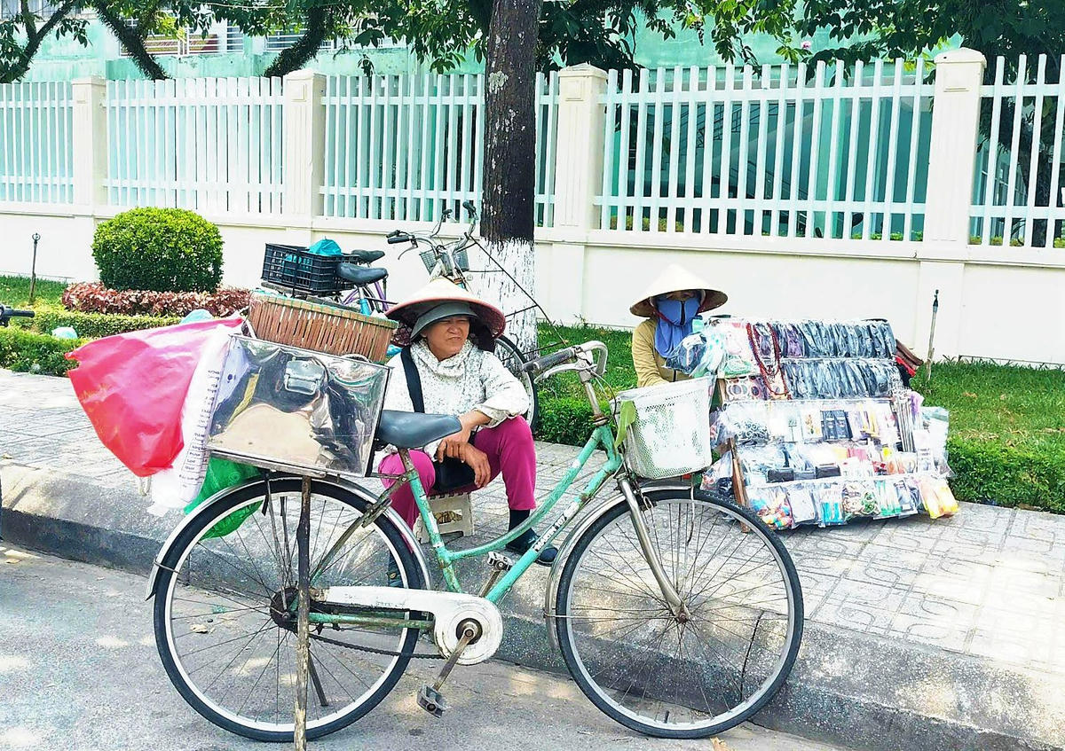 Người bán hàng rong ngôi nghỉ dưới bóng cây ở đường Nguyễn Du, phường Tam Kỳ. Ảnh: Chí Đại.