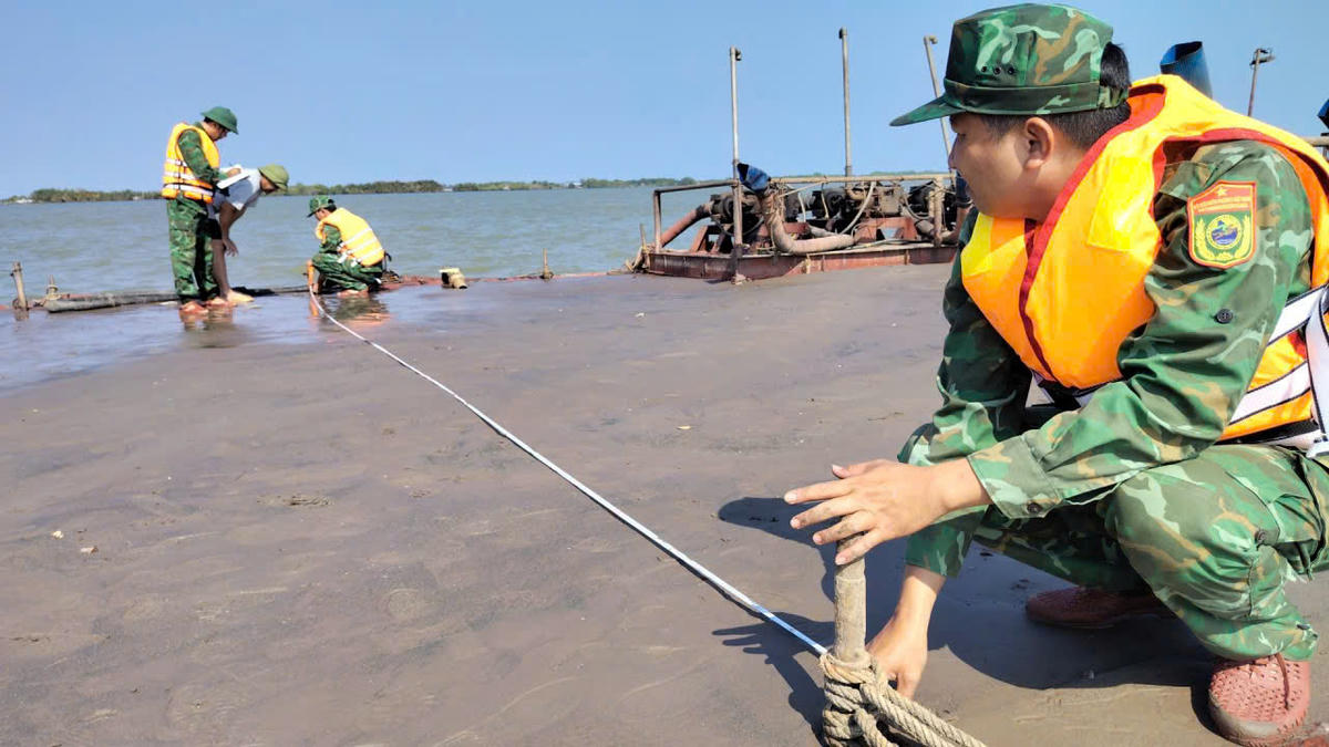 Cán bộ Đồn Biên phòng Cổ Chiên phối hợp lực lượng chức năng kiểm tra, đo đạc khối lượng cát trên phương tiện vi phạm để phục vụ công tác xác minh, xử lý theo quy định pháp luật. (Ảnh: Xuân Lộc).