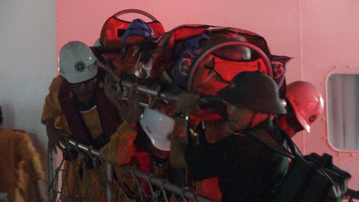 Đưa nạn nhân từ tàu SAR 631 lên bờ trong khuya 17/4. Ảnh: Văn Thuần.