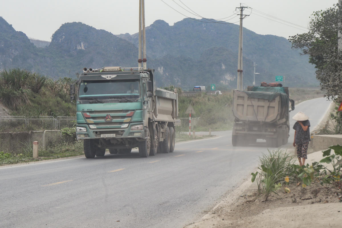 Quá trình di chuyển từ mỏ qua đường gom cao tốc, nhiều xe tải kéo bụi, khiến người dân sống ven đường bị ảnh hưởng. Ảnh: Đình Minh