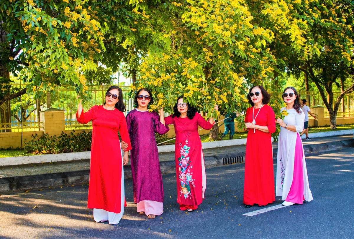 Những người phụ nữ check in hoa sưa ở đường Trần Hưng Đạo. Ảnh: Chí Đại.