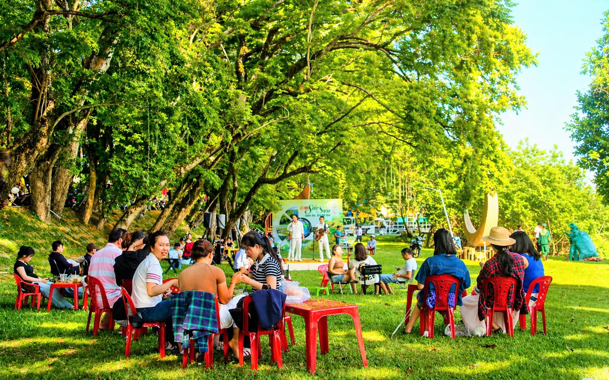 Nhiều người vui chơi, nghỉ mát dưới hàng sưa vàng ở làng Hương Trà. Ảnh: Chí Đại.