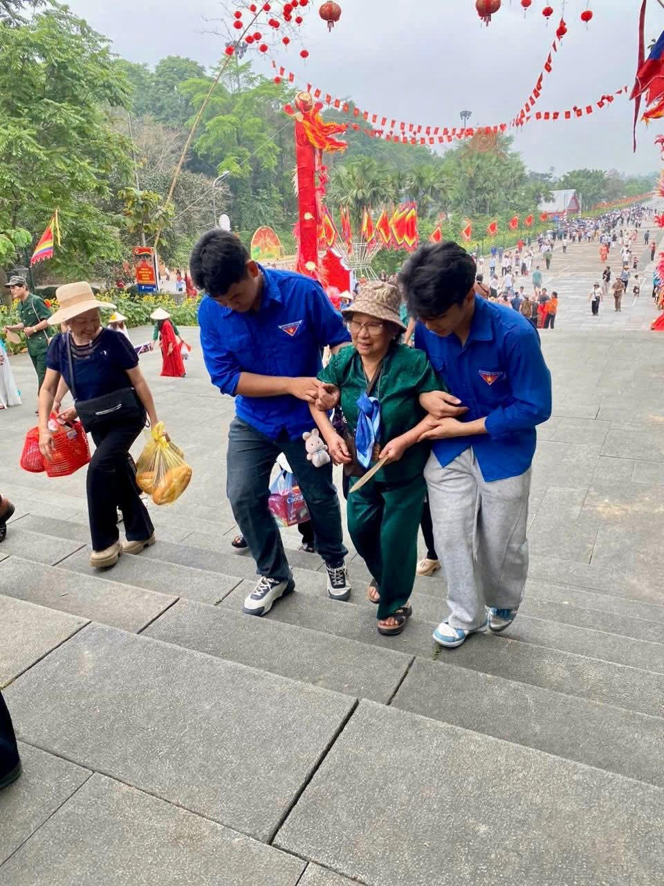 Hỗ trợ người già lên Đền. Ảnh: TD.