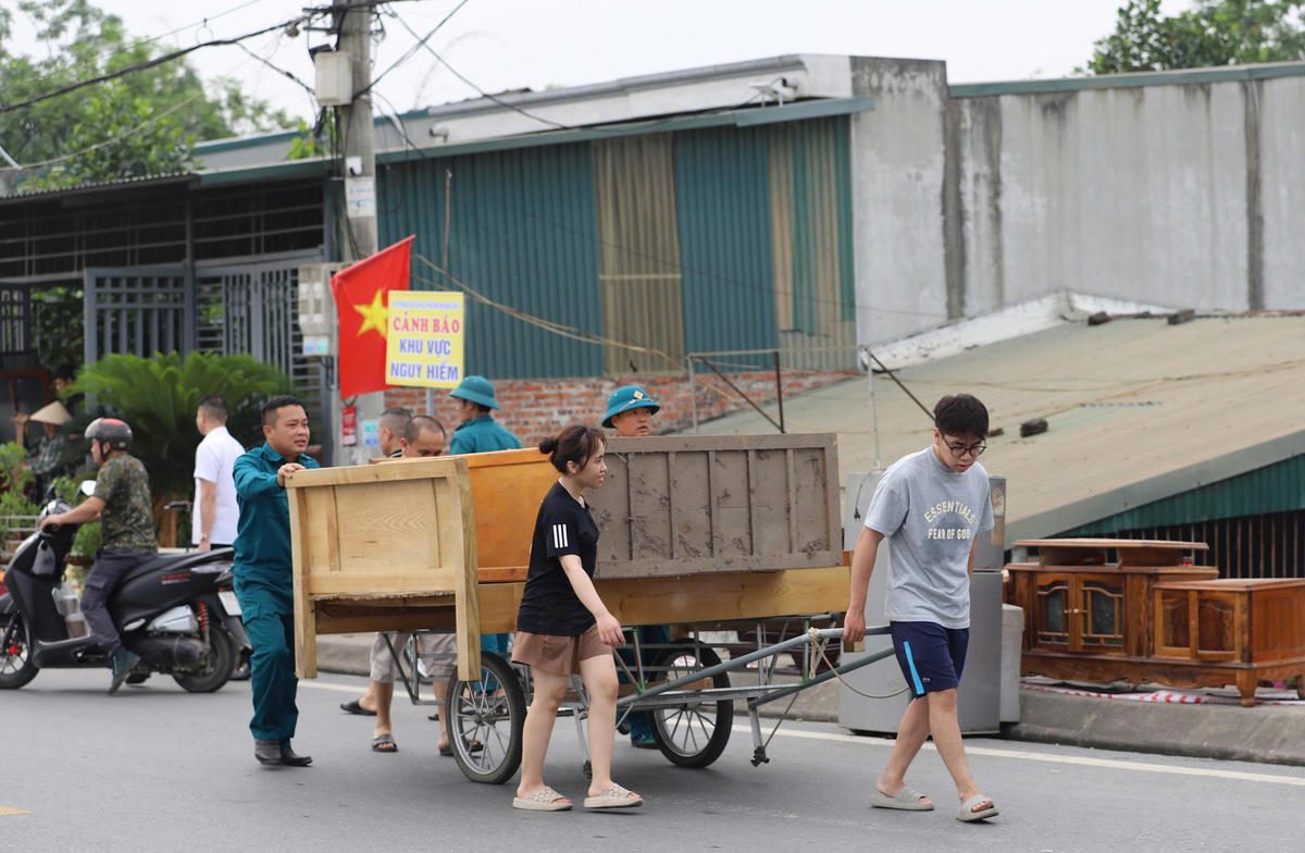 Lực lượng chức năng hỗ trợ người dân di dời tài sản ra khỏi khu vực nguy hiểm. Ảnh: Đ.A.
