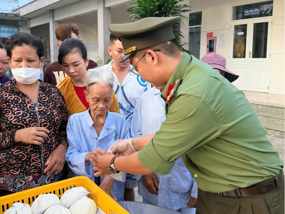 Đoàn viên thanh niên Công an tỉnh An Giang trao suất ăn tận tay cho người bệnh lớn tuổi. Ảnh: Văn Vũ