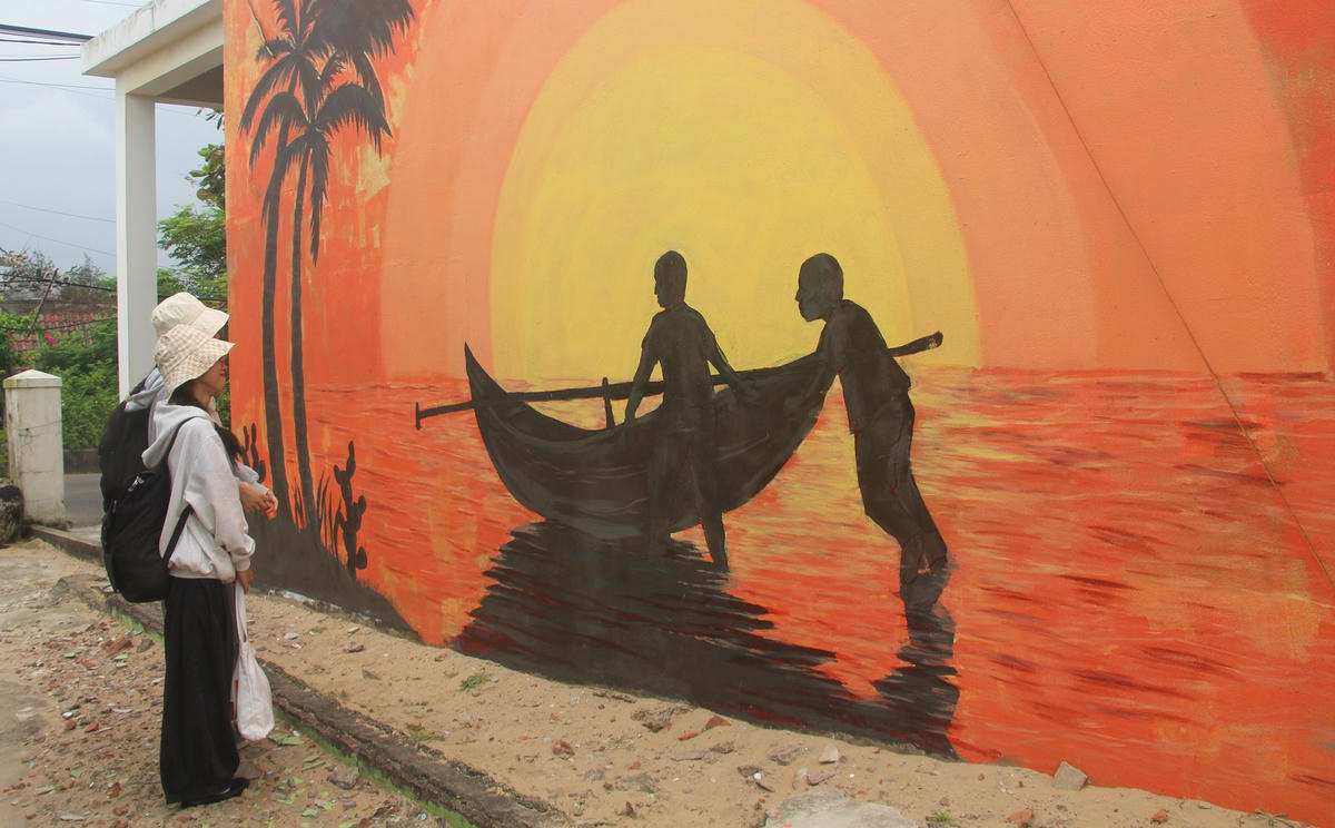 Du khách Kiều My (bên phải) đang xem một bức tranh ở Làng bích họa Tam Thanh. Ảnh: Nguyễn Tín.