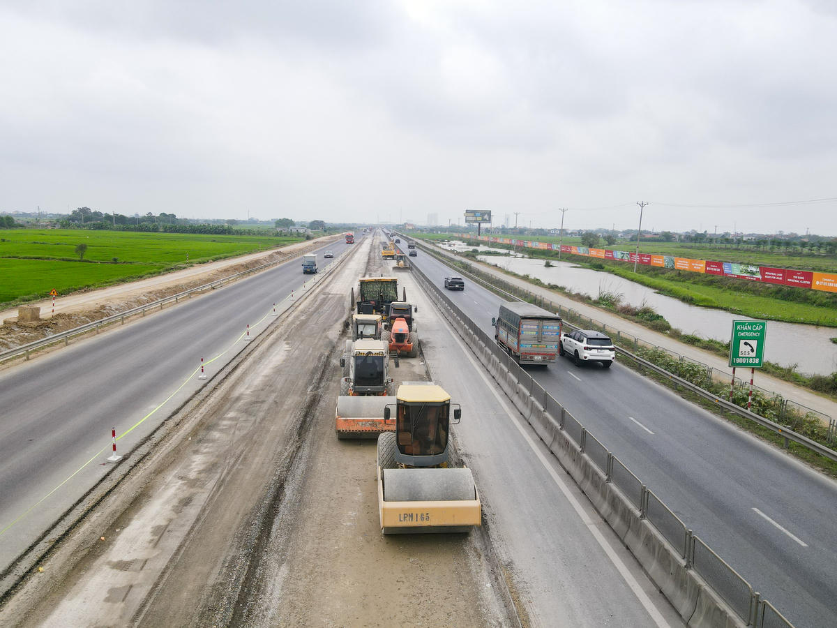 Nhiều đoạn đang được thảm bê tông nhựa, từng bước hình thành diện mạo tuyến cao tốc mở rộng. Hệ thống hạ tầng kỹ thuật như ống cáp, bể cáp ITS cũng đang được triển khai song song. Ảnh: Đình Minh