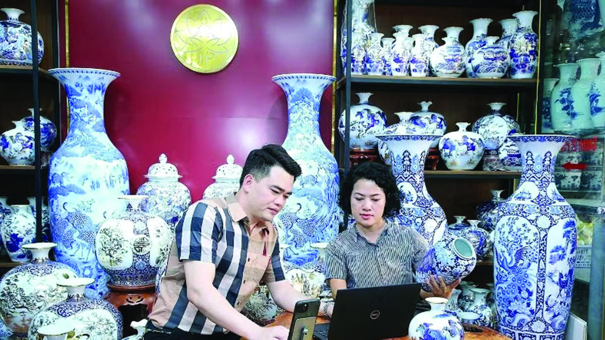 Nghệ nhân Trần Trung Hiếu (Bát Tràng, Hà Nội) cùng đồng nghiệp thảo luận cách đưa sản phẩm làng nghề lên các nền tảng thương mại điện tử.