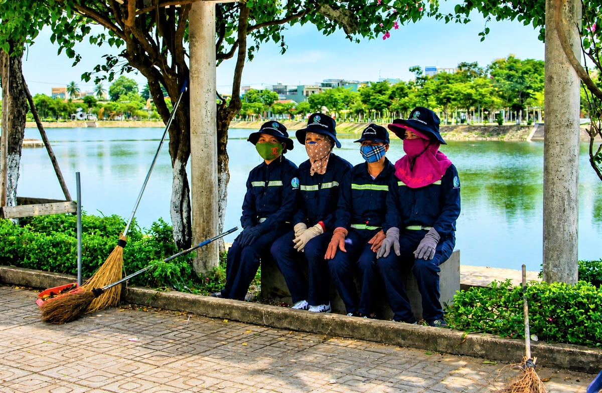 Công nhân ngồi nghỉ trưa ở bờ hồ Nguyễn Du. Ảnh: Tấn Thành.