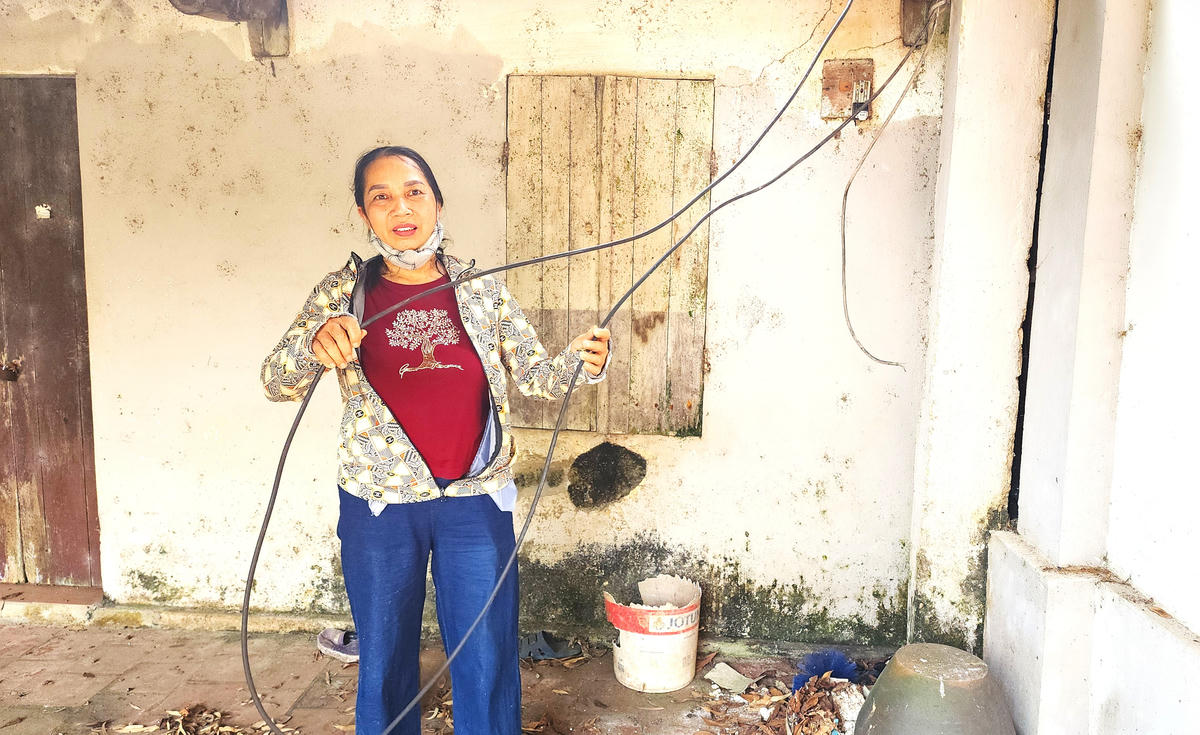 Bà Đặng Thị Dậu bên đoạn dây điện bị kẻ trộm cắt dở. Ảnh: K.H.