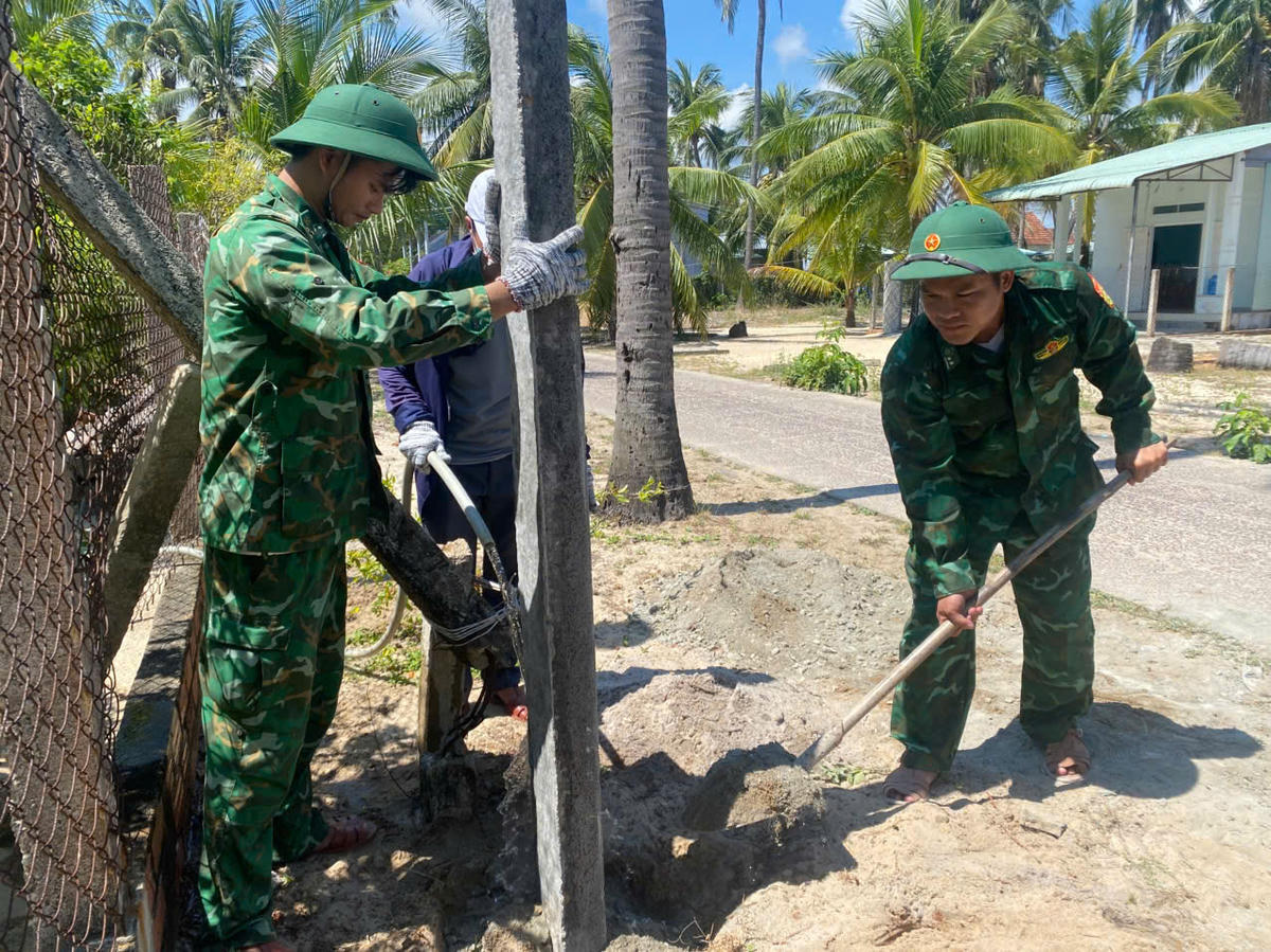 Cán bộ, chiến sĩ Đồn Biên phòng Xuân Hoà phối hợp cùng lực lượng địa phương tham gia dựng cột điện. Ảnh: Thùy Dung.