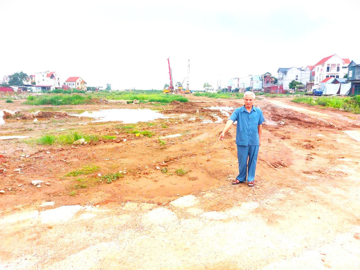 Ông Nguyễn Văn Đường bên thửa đất từng được ông đổi cho UBND xã Văn Khê để làm đường nông thôn. Nay diện tích đất này nằm trong Dự án Đường Vành đai 4. Ảnh: K.H.