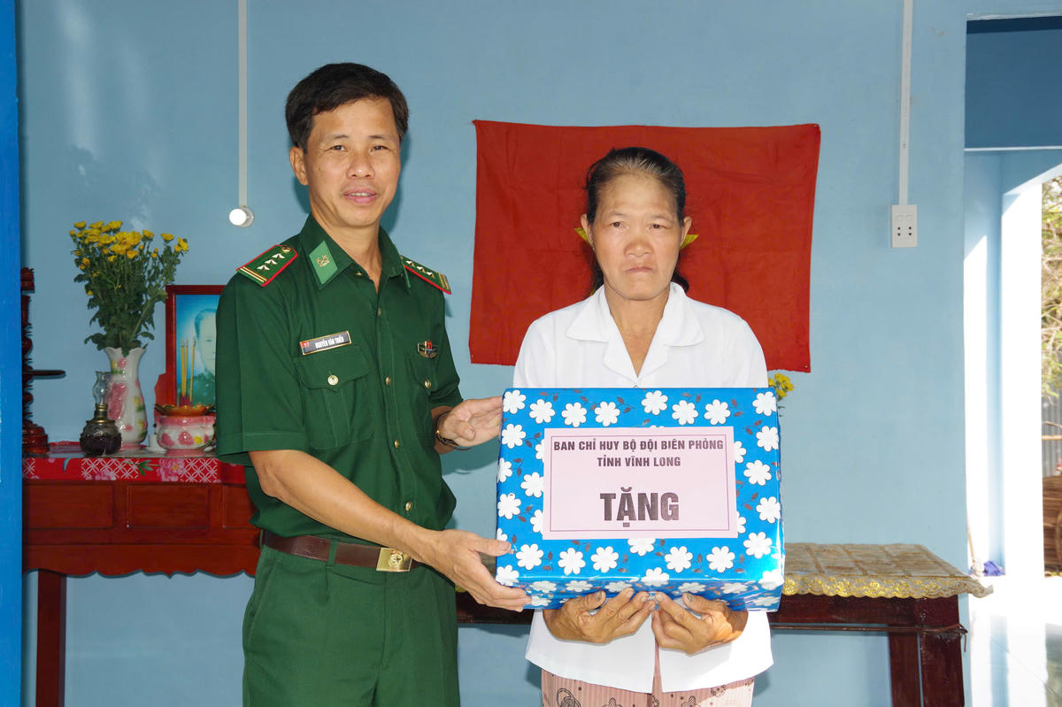 Thượng tá Nguyễn Văn Triều, Phó Chính ủy Ban Chỉ huy Bộ đội Biên phòng tỉnh Vĩnh Long tặng quà chúc mừng hộ dân vừa được hỗ trợ mái ấm mới. (Ảnh: Trần Giỏi).