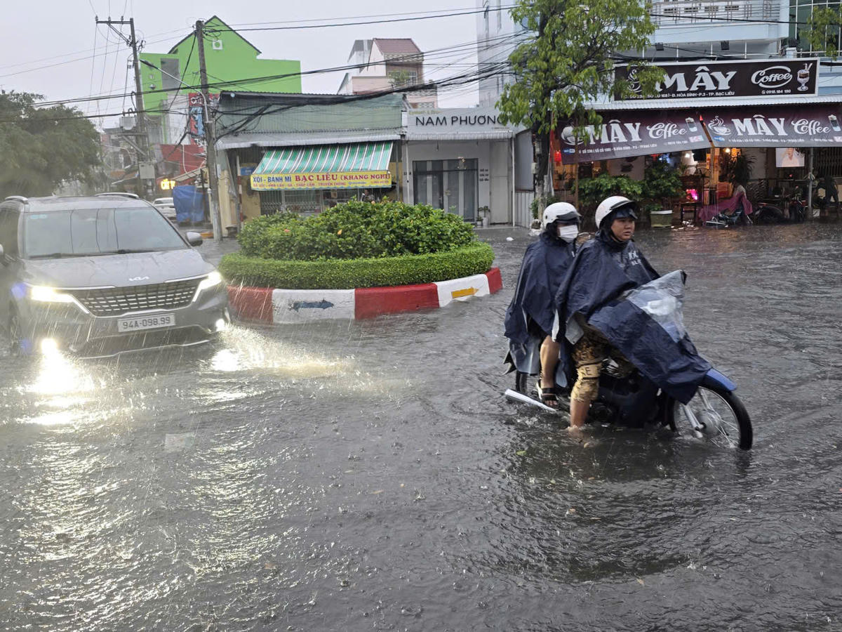 Cơn mưa đầu mùa gây ngập nặng, người dân vất vả di chuyển trong 'biển nước'. Ảnh: Nguyên Du