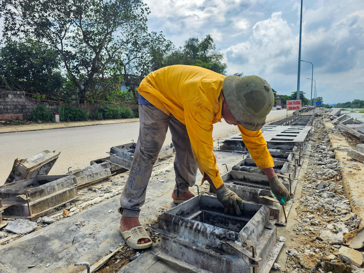 Một công nhân đang thực hiện việc đúc cấu kiện bê tông lát mái kè ngay tại công trường. Ảnh: Đình Minh