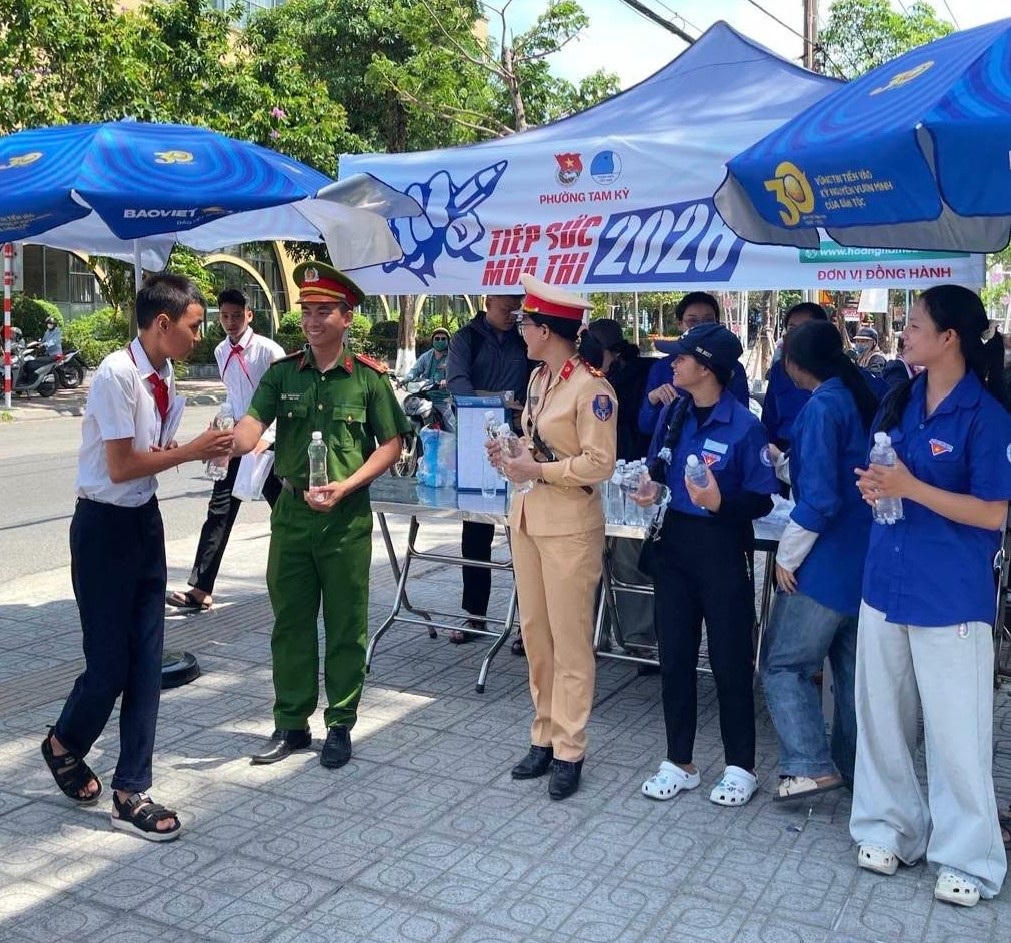 Lực lượng Công an phường Tam Kỳ tiếp sức thí sính dự thi trước cổng trường. Ảnh: CA.