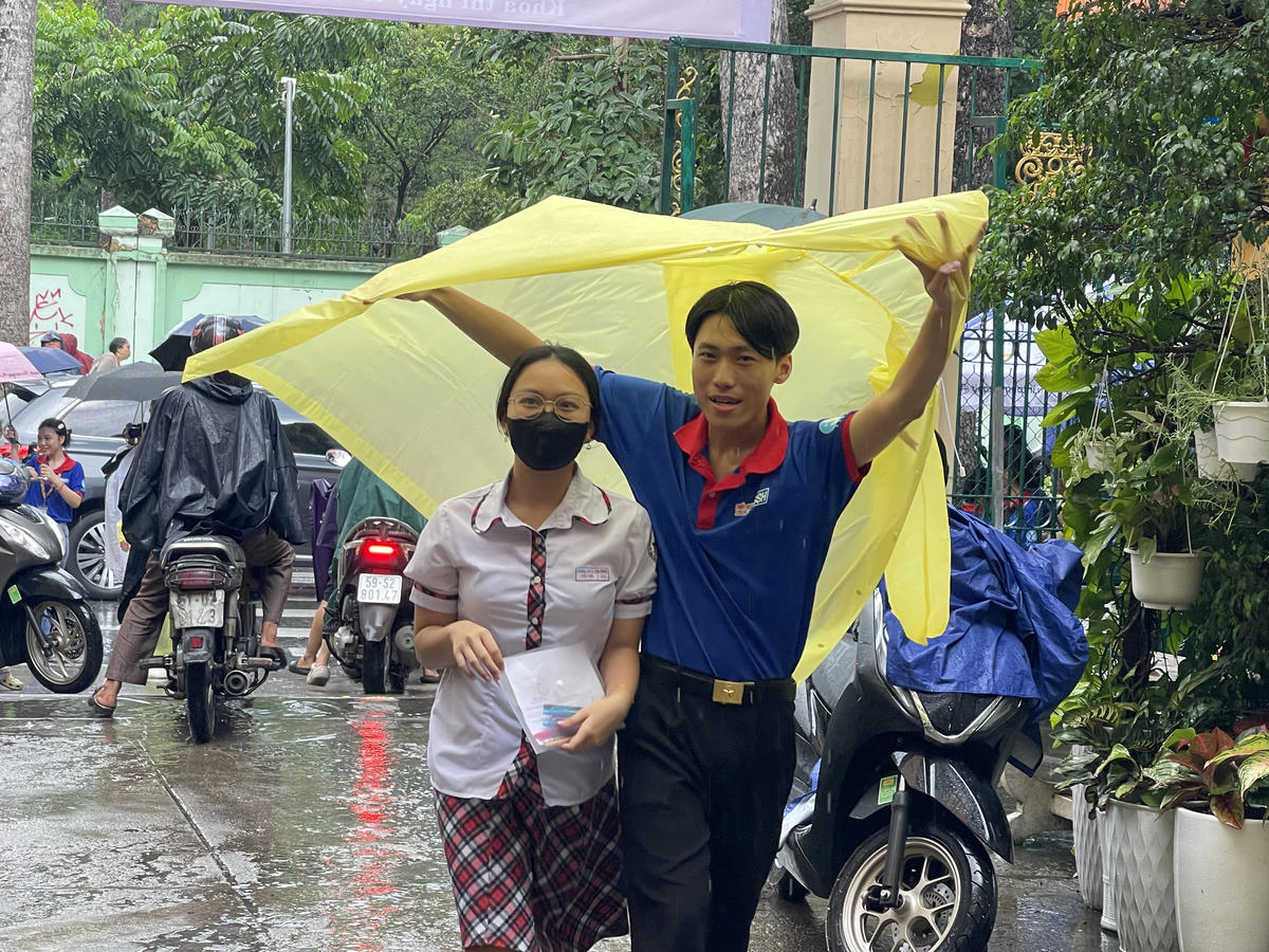 Trời bất ngờ đổ mưa ở khu vực trung tâm nên nhiều thí sinh được lực lượng tình nguyện hỗ trợ che mưa. Ảnh: Đ.Xá.