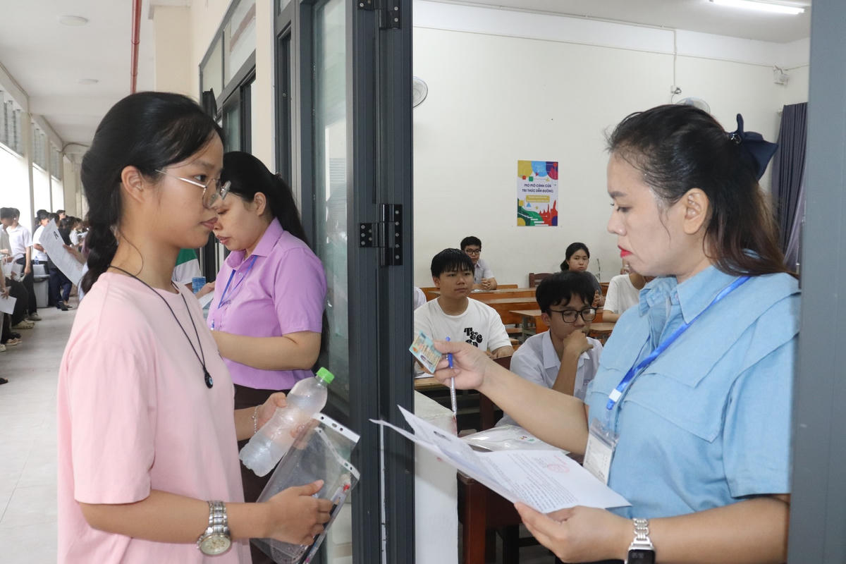 Cán bộ coi thi kiểm tra giấy tờ thí sinh trước khi vào phòng thi. Ảnh: NH.