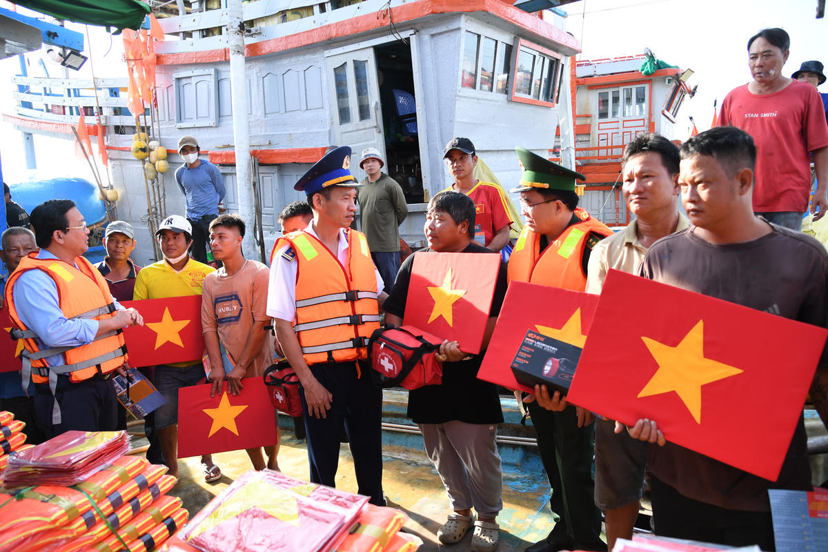 Đại tá Lê Vă Tú, Chính ủy Bộ Tư lệnh Vùng Cảnh Sát biển 3 cùng lãnh đạo địa phương trao cờ Tổ quốc, đèn pin, áo phao cho ngư dân. Ảnh: Văn Thoan.