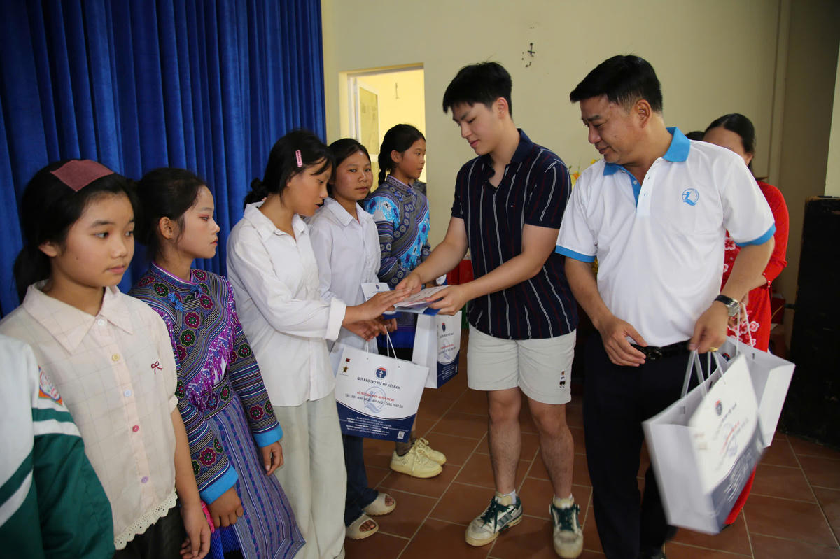 Ông Đinh Tiến Hải - Giám đốc Quỹ Bảo trợ trẻ em Việt Nam và em Nguyễn Huỳnh Nghị tặng quà và học bổng cho trẻ em có hoàn cảnh đặc biệt, khó khăn xã Mường Khương, tỉnh Lào Cai. Ảnh: Vương Long