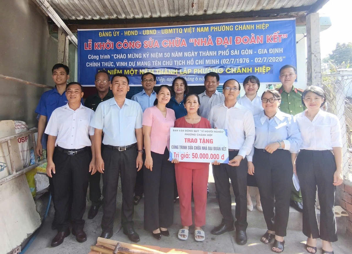 Lãnh đạo phường trao bảng tượng trưng hỗ trợ sửa chữa nhà cho gia đình bà Lê Thị Cho. Ảnh: HC.