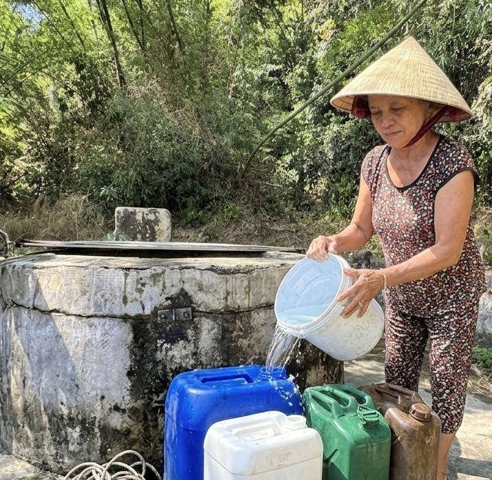 Bà Nguyễn Thị Lan đang múc nước từ giếng cổ về cho gia đình sử dụng sinh hoạt. Ảnh: NT.