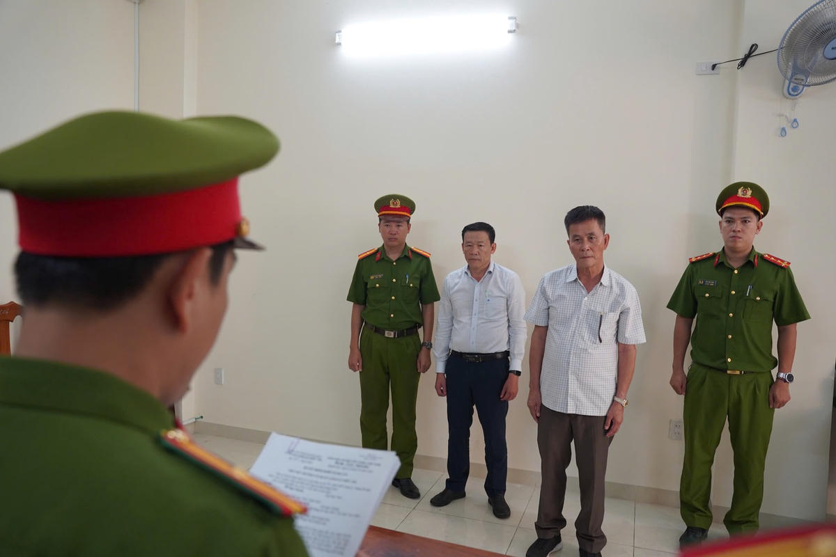 Cơ quan Cảnh sát điều tra Công an tỉnh Khánh Hòa tống đạt các quyết định đối với Trần Huỳnh Kiến Trúc (áo trắng) và Đỗ Ngọc Quang (áo ca rô).