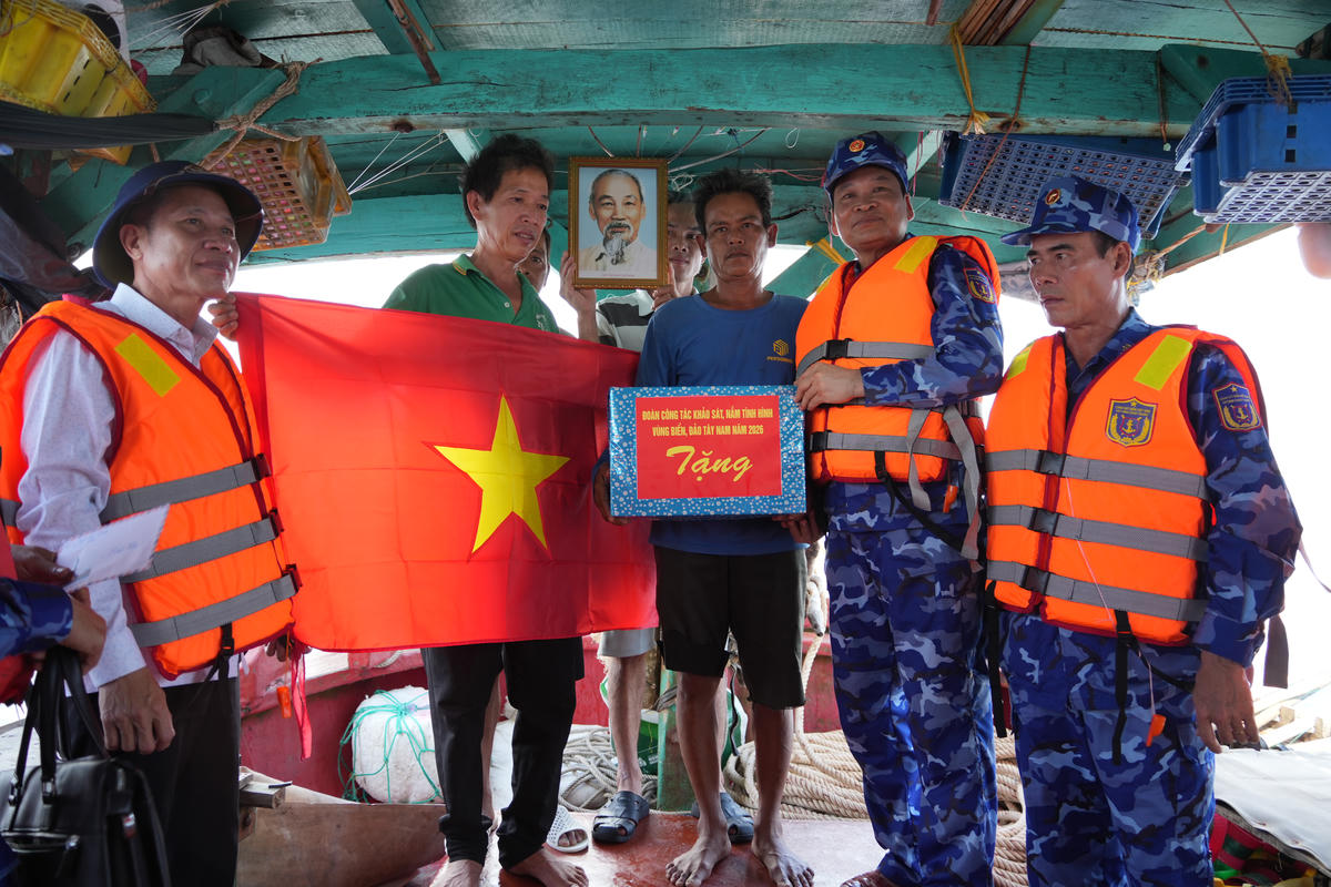 Thiếu tướng Trần Văn Xuân, Phó Chính uỷ Cảnh sát biển Việt Nam (thứ hai từ phải sang) và Trưởng ban Nội chính Tỉnh uỷ Cà Mau Trần Hữu Phước (bìa trái) trao tặng cờ Tổ quốc, ảnh Bác Hồ và quà cho ngư dân đang khai thác hải sản trên vùng biển Tây Nam trong chuyến khảo sát, nắm tình hình biển, đảo Tây Nam năm 2026. Ảnh: Nguyên Du