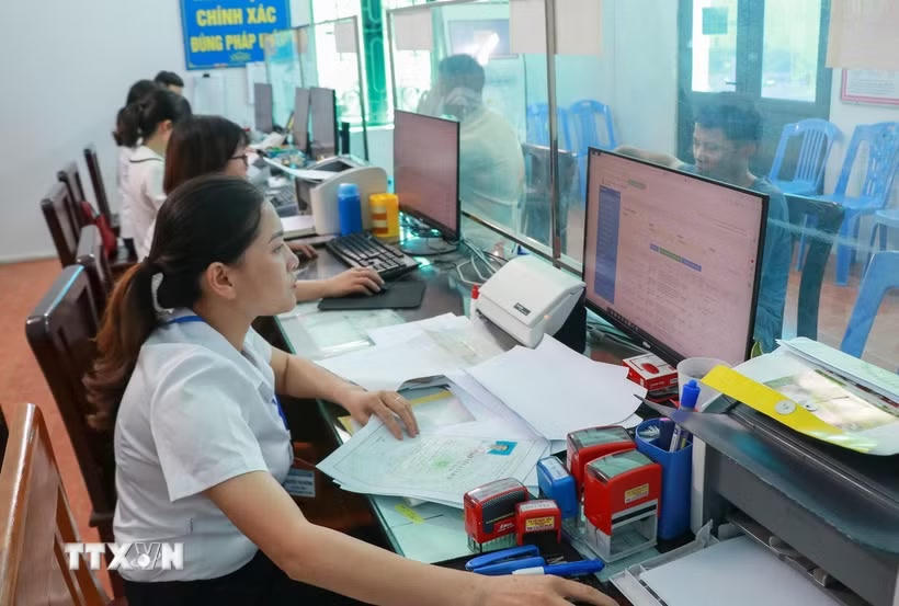 Cán bộ Trung tâm phục vụ hành chính công xã Nam Minh, tỉnh Ninh Bình làm thủ tục cho người dân. (Ảnh: Công Luật/TTXVN).