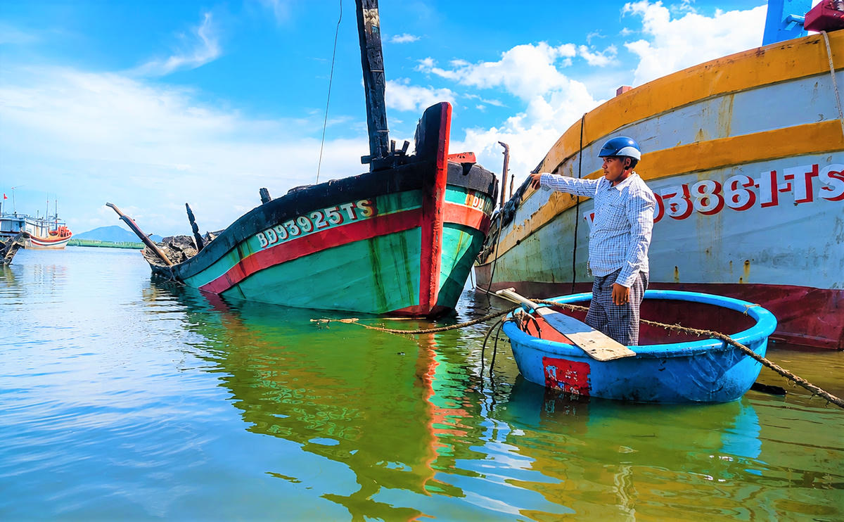 Ngư dân Lê Văn Sang đứng nhìn tàu cá BĐ 93925 TS bị cháy đen trơ khung. Ảnh: ĐS.