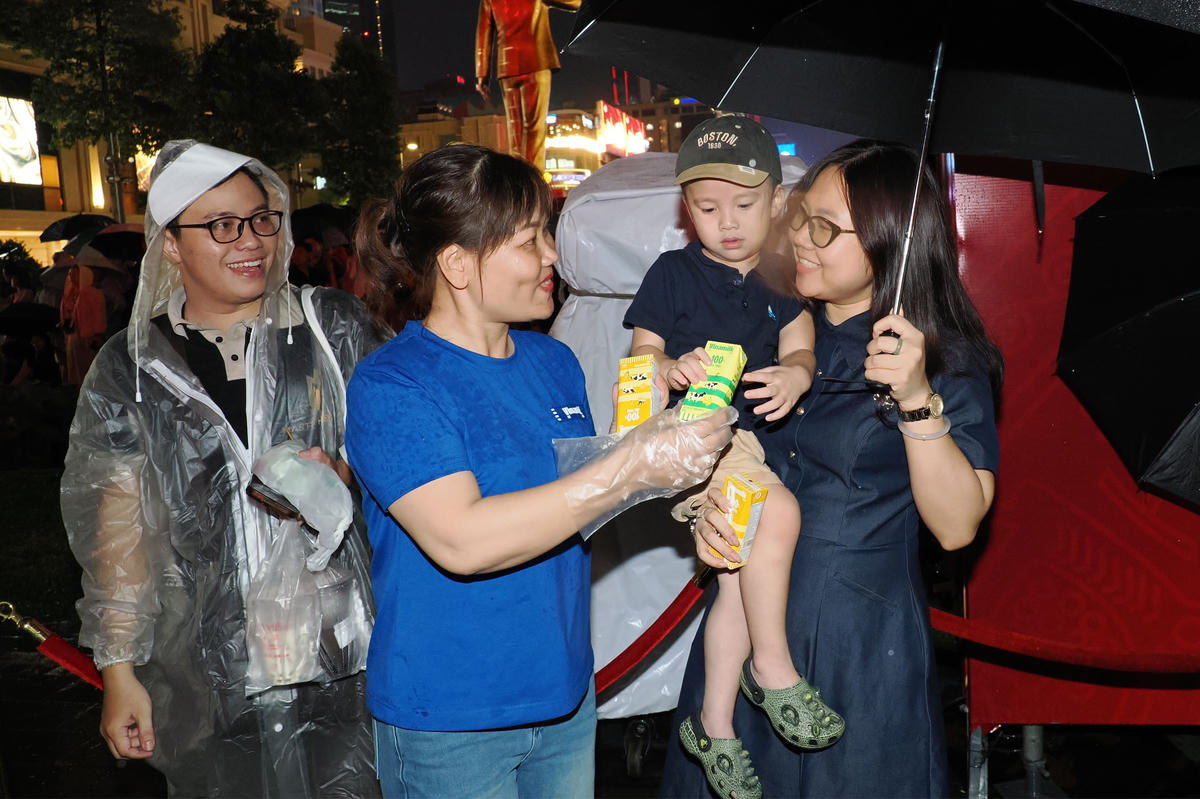 Sau giờ làm việc, nhiều nhân viên Vinamilk đã tình nguyện có mặt tại các trạm tiếp năng lượng từ rất sớm để chuẩn bị sản phẩm gửi đến người dân. Dù cơn mưa bất chợt đổ xuống vào đầu giờ tối, những chiếc áo xanh Vinamilk vẫn kiên trì đứng tại các điểm phát sữa, tay trao từng hộp sữa, chai nước cùng những lời hỏi han, động viên thân tình.