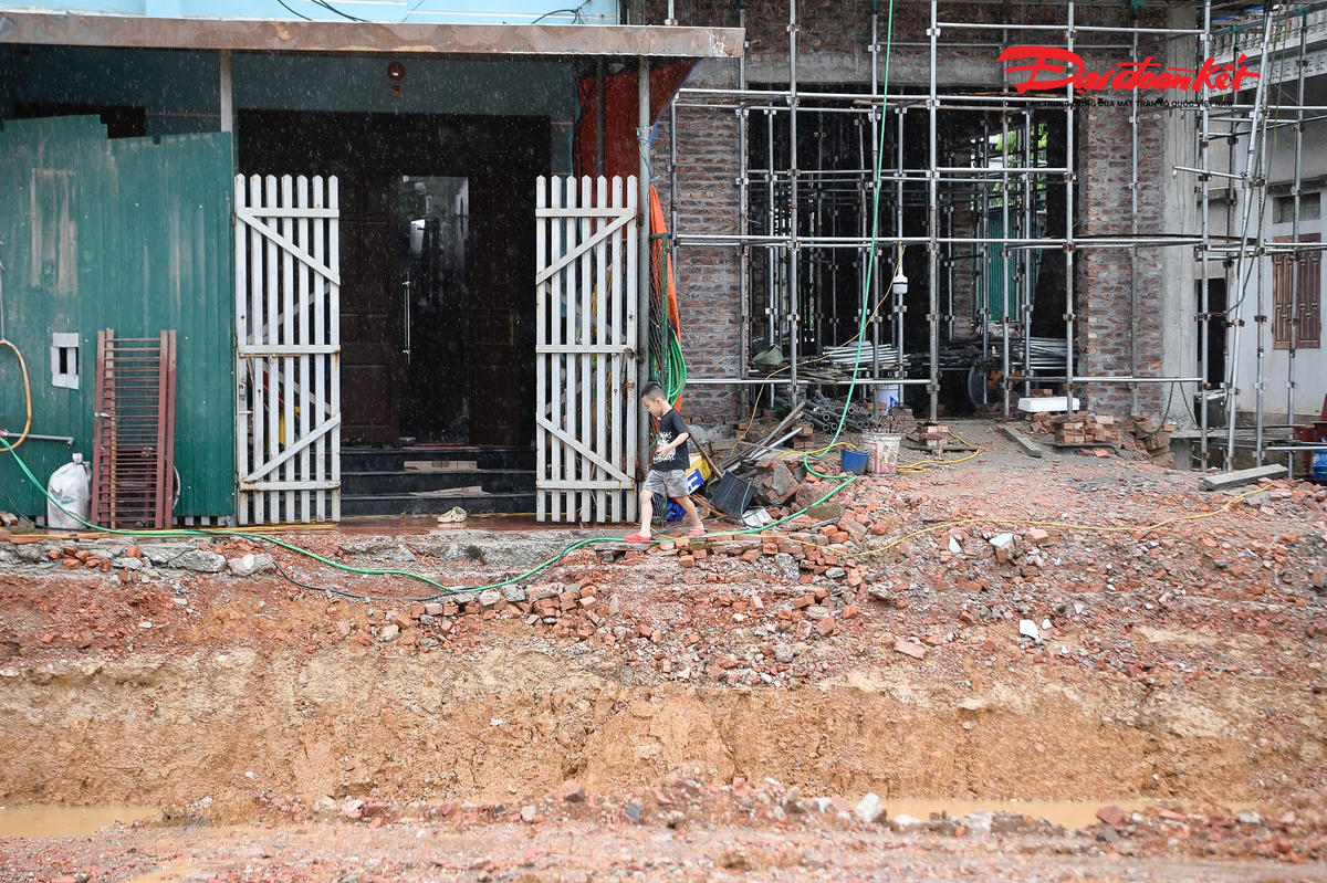 Lối đi chật hẹp sát mép hố đào sâu buộc người dân, trong đó có nhiều trẻ nhỏ, phải di chuyển trong điều kiện tiềm ẩn nhiều rủi ro. Phía dưới là khu vực nước đọng sau mưa.
