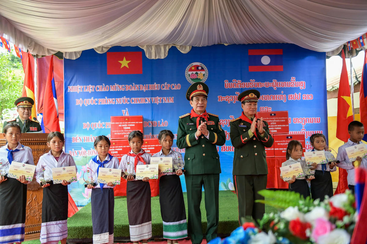 Đại tướng Phan Văn Giang và Đại tướng Khamliang Outhakaysone trao quà tặng các em học sinh Trường Tiểu học Thông-năm-mun, bản Xốp-tờng. Ảnh: Nam Trần