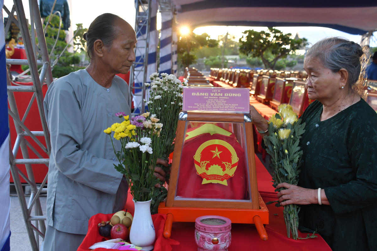 Bà Đặng Thị Bé và ông Đặng Văn bên hài cốt em trai là liệt sĩ Đặng Văn Dừng vừa được Đội K93 tìm kiếm, quy tập và xác định danh tính. Ảnh: CTV