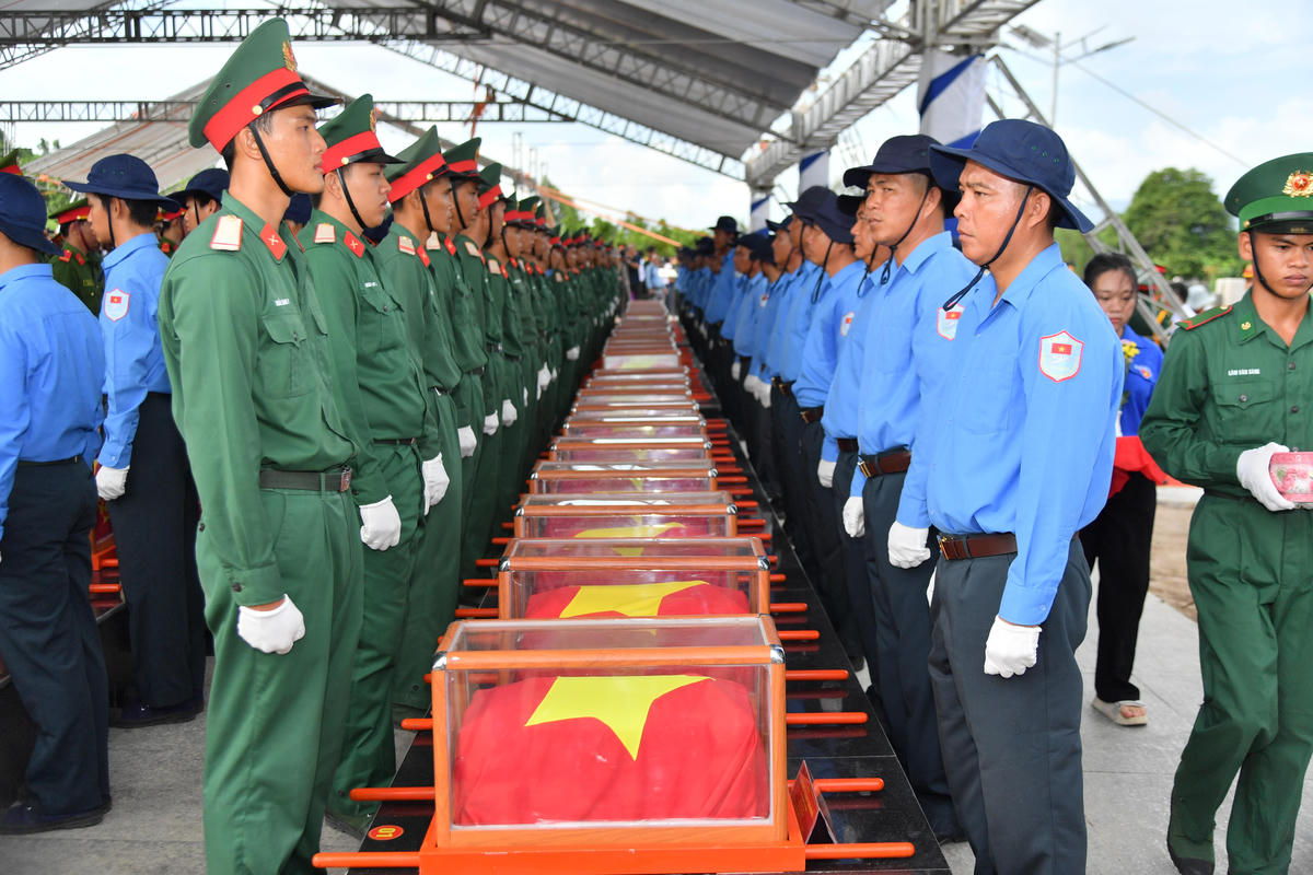 Sau lễ truy điệu, trong tiếng nhạc trầm hùng và sự chứng kiến của các đồng chí lãnh đạo, thân nhân liệt sĩ cùng đông đảo cán bộ, chiến sĩ và Nhân dân, Tổ Quân kỳ, Đội danh dự, các lực lượng tiêu binh cùng cán bộ, chiến sĩ Đội K90 (Cục Chính trị Quân khu 9), Đội K92, Đội K93 (Bộ Chỉ huy Quân sự tỉnh An Giang), Trung đoàn 892, Công an tỉnh, Bộ đội Biên phòng, đoàn viên thanh niên và các lực lượng phục vụ đã trang trọng di chuyển 235 hài cốt liệt sĩ đến khu vực an táng. Ảnh: Phương Vũ