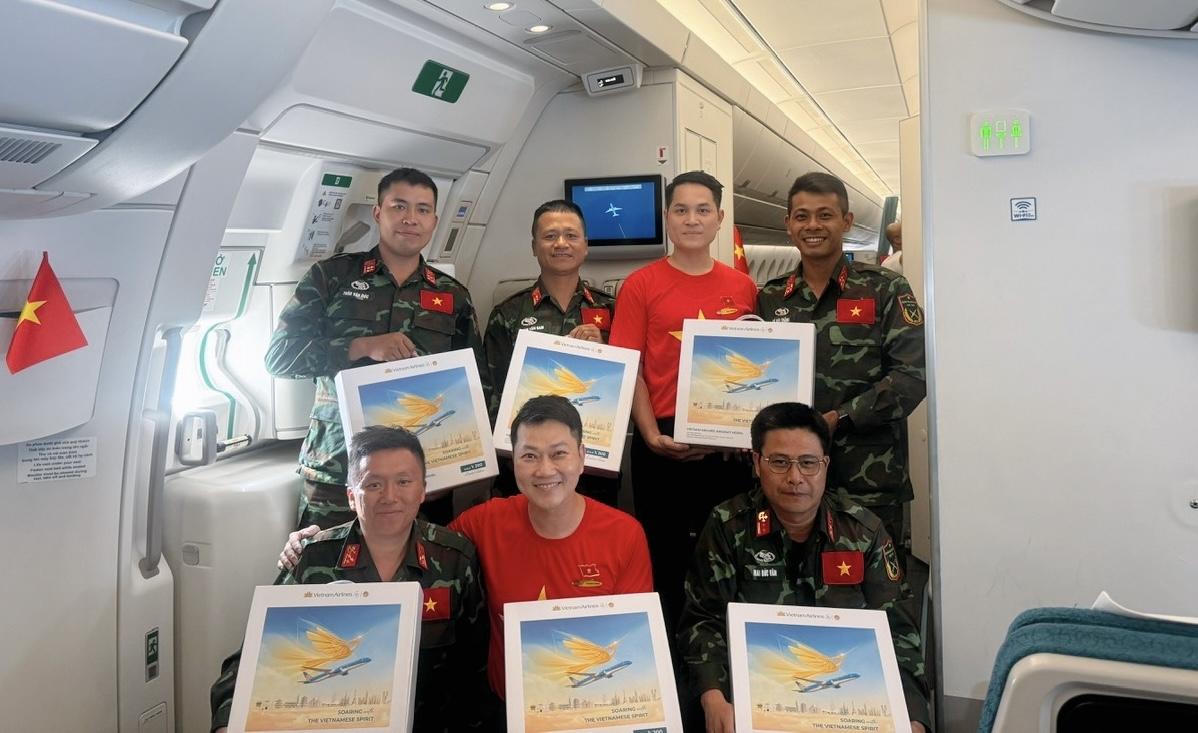 Trên chuyến bay, các tiếp viên của Vietnam Airlines mặc áo và cài huy hiệu cờ đỏ sao vàng, mang theo sắc màu Tổ quốc trong không gian khoang bay. Hình ảnh ấy hòa chung vào không khí trang trọng của hành trình, như một lời cảm ơn gửi đến các cán bộ, chiến sĩ đã hoàn thành xuất sắc nhiệm vụ và trở về trong niềm tự hào.