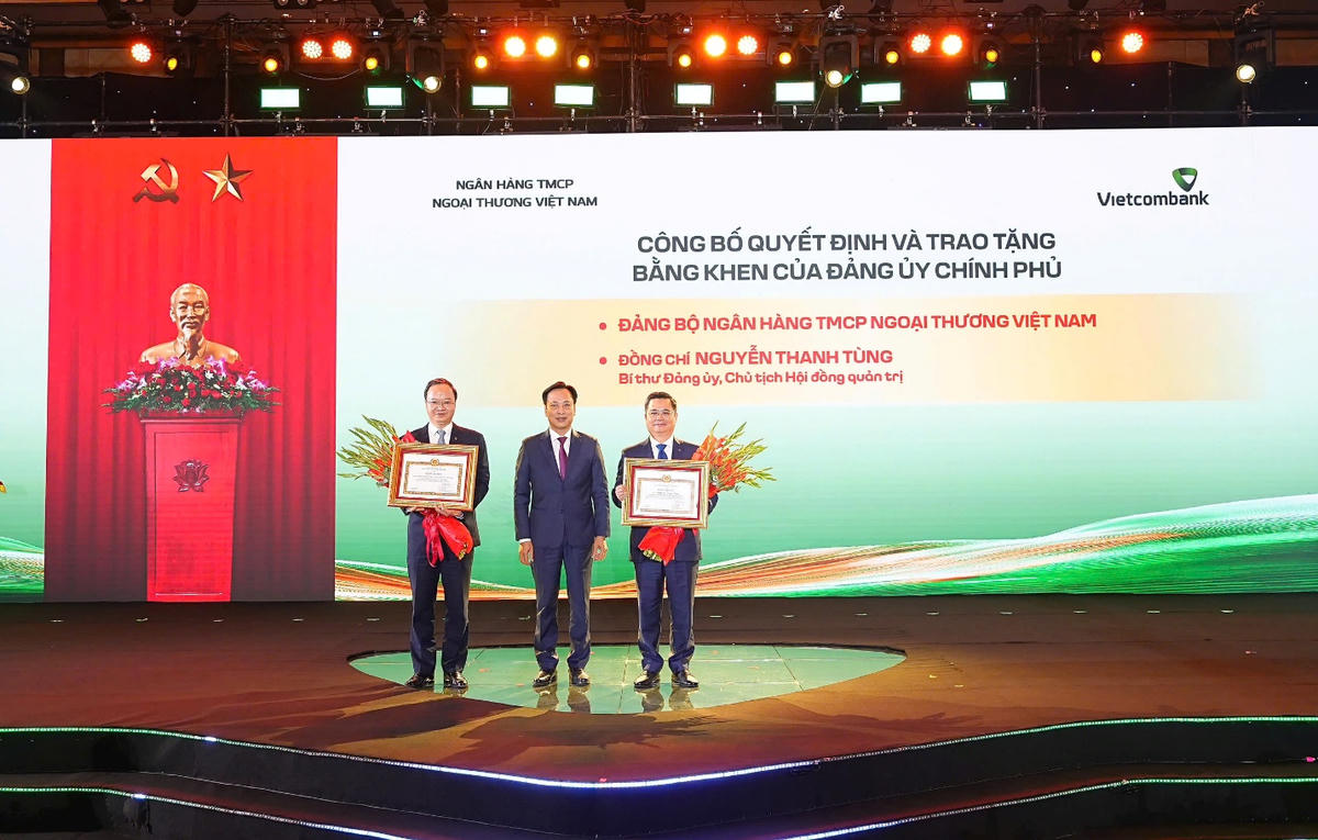 Đại diện Đảng ủy Chính phủ, đ/c Lại Xuân Lâm - Phó Bí thư Chuyên trách trao bằng khen của Đảng ủy Chính phủ tặng Đảng bộ Vietcombank vì đã có thành tích xuất sắc, tiêu biểu hoàn thành vượt mức các chỉ tiêu Nghị quyết Đại hội nhiệm kỳ 2020-2025 và tặng bằng khen cho cá nhân đ/c Nguyễn Thanh Tùng - Bí thư Đảng ủy, Chủ tịch HĐQT Vietcombank (ngoài cùng bên phải) vì những thành tích xuất sắc trong thực hiện Nghị quyết Đại hội nhiệm kỳ 2020-2025. Đ/c Lê Quang Vinh - Phó Bí thư Đảng ủy, Thành viên HĐQT, Tổng Giám đốc (ngoài cùng bên trái) đại diện Đảng bộ Vietcombank nhận bằng khen tập thể