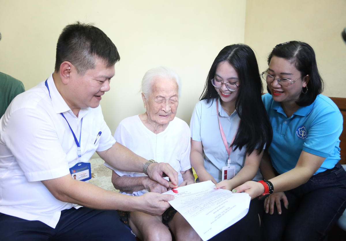 Cán bộ UBND phường Văn Miếu - Quốc Tử Giám, Trung tâm Phục vụ hành chính công Chi nhánh số 3 và BHXH cơ sở Hoàn Kiếm hỗ trợ cụ Nguyễn Thị Mùi hoàn thiện thủ tục ủy quyền nhận lương hưu tại nhà.
