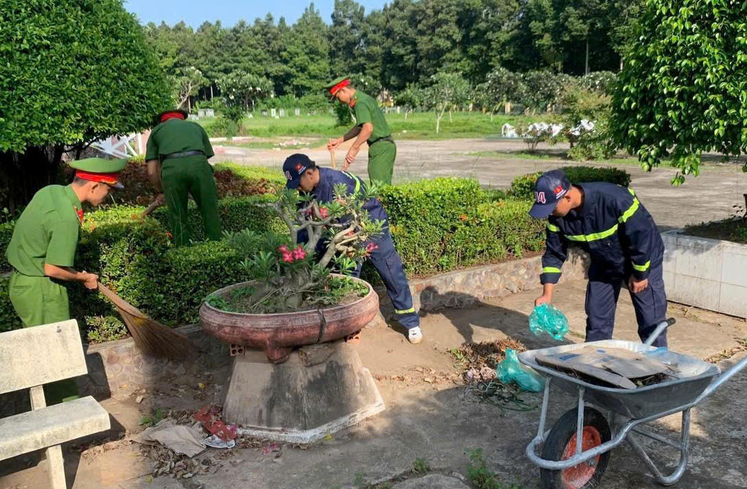 Lực lượng công an vệ sinh, chỉnh trang nghĩa trang. Ảnh: Tiến Dũng