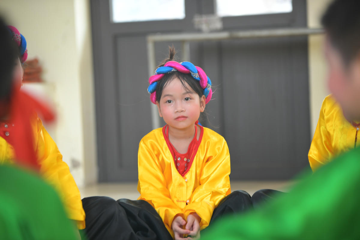 Em nhỏ chăm chú lắng nghe những lời truyền đạt của các nghệ nhân.