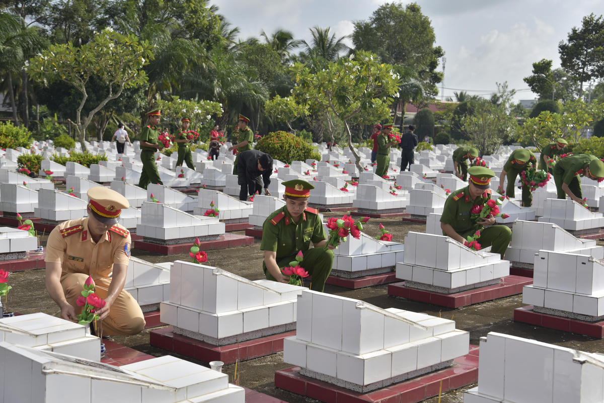 Lực lượng công an thay mới hoa và lọ hoa trên từng phần mộ liệt sĩ. Ảnh: Tỉnh đoàn An Giang