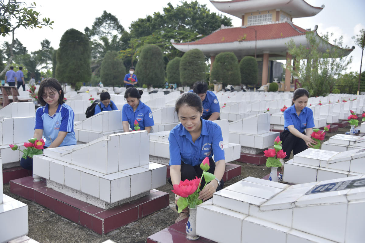 Các đoàn viên, thanh niên thay mới hoa và lọ hoa trên từng phần mộ liệt sĩ. Ảnh: Tỉnh đoàn An Giang